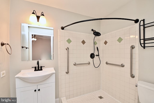 bathroom featuring ceiling fan, toilet, tiled shower, and vanity