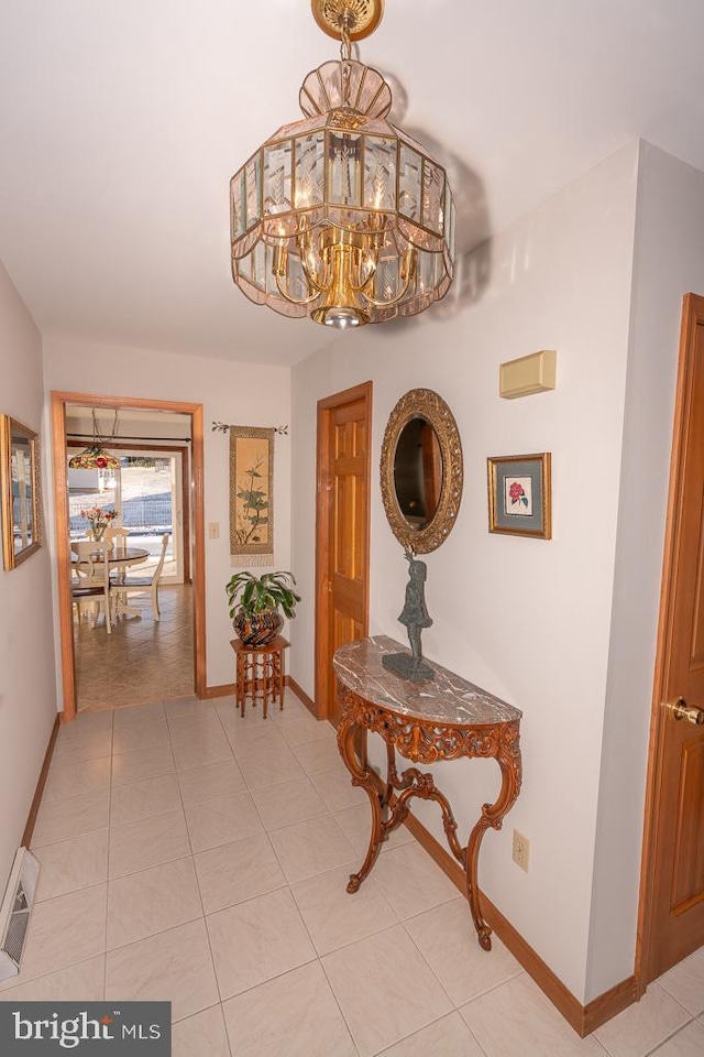 hall with light tile patterned floors and an inviting chandelier