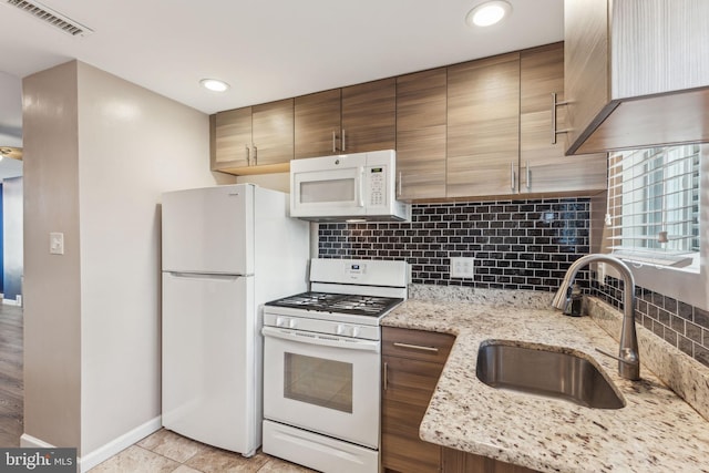 kitchen featuring white appliances, backsplash, sink, light stone countertops, and light tile patterned floors