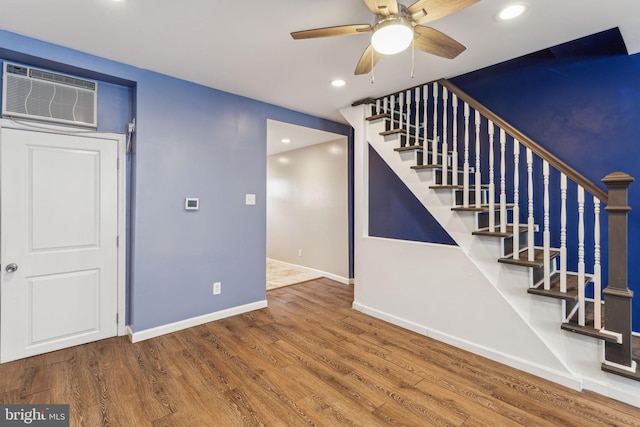 stairs featuring a wall mounted air conditioner, hardwood / wood-style floors, and ceiling fan