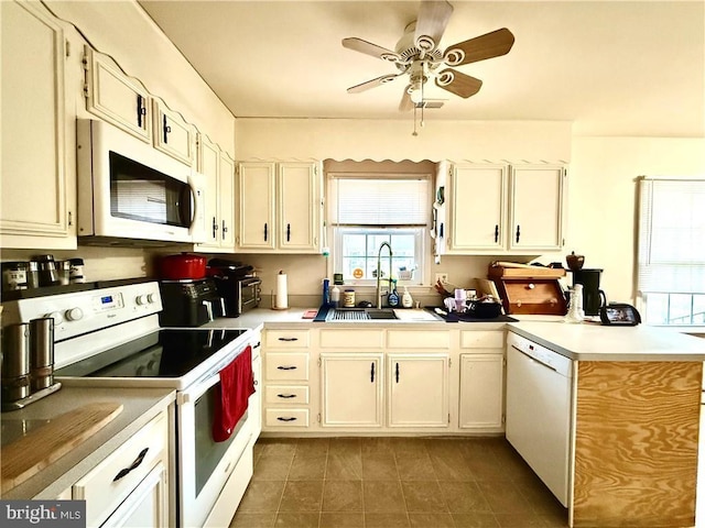 kitchen featuring a sink, white appliances, a peninsula, and light countertops