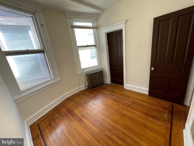 spare room with hardwood / wood-style flooring, lofted ceiling, and radiator