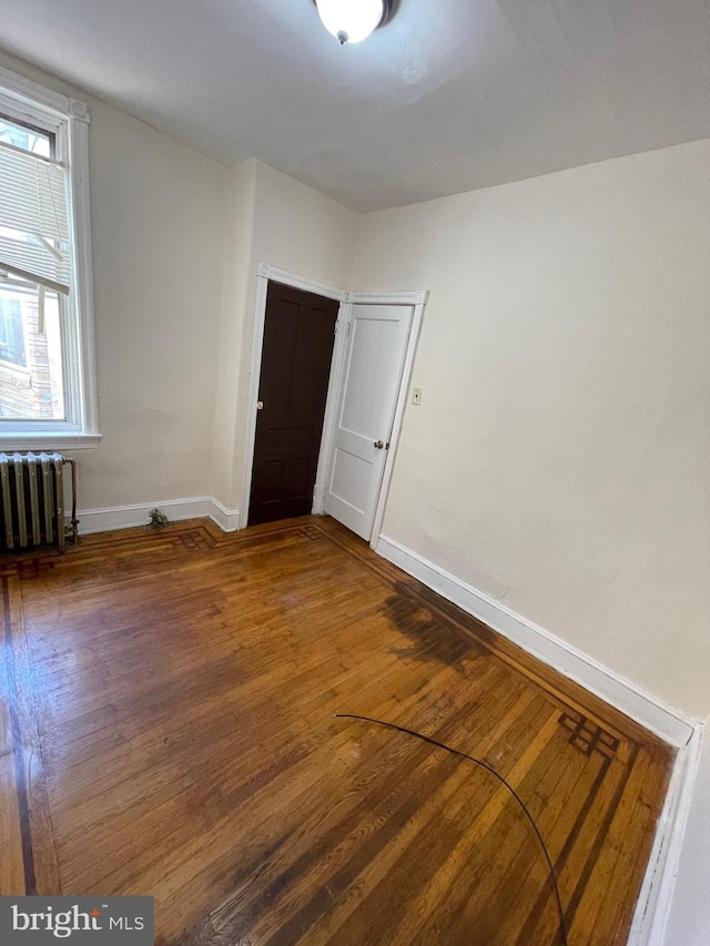 spare room featuring dark hardwood / wood-style flooring and radiator heating unit