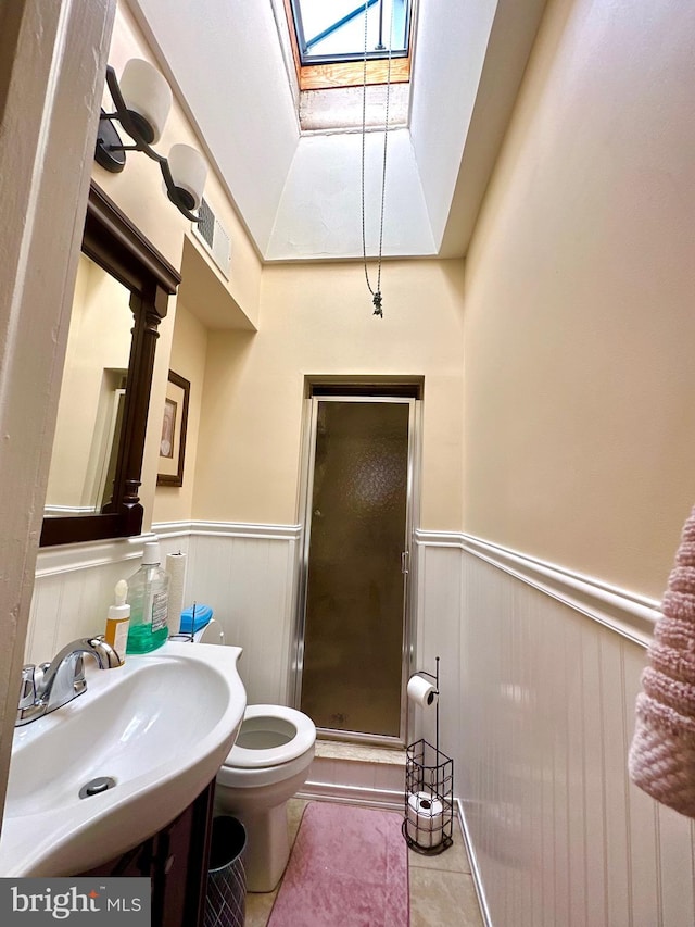 bathroom featuring tile patterned floors, sink, a skylight, toilet, and walk in shower