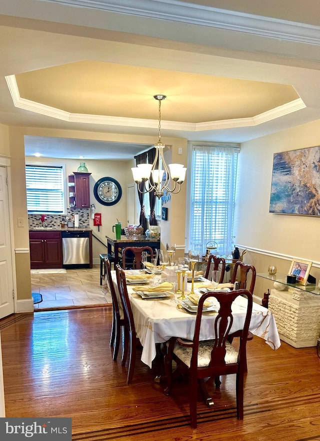 dining space featuring an inviting chandelier, light wood-type flooring, crown molding, and a tray ceiling