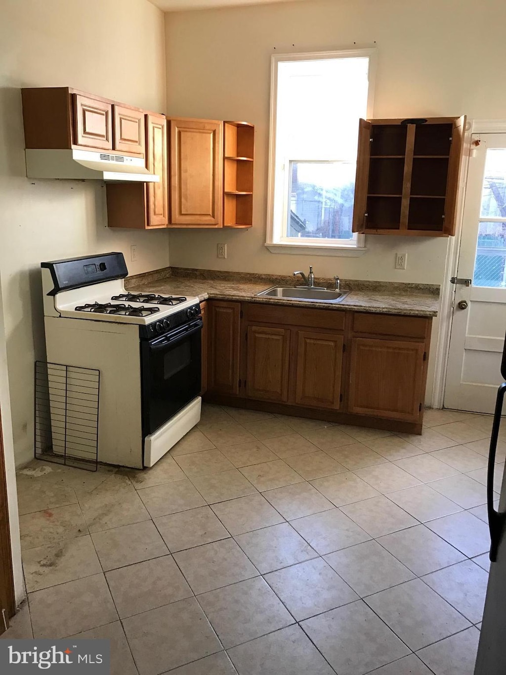 kitchen with white range with gas stovetop, light tile patterned floors, and sink