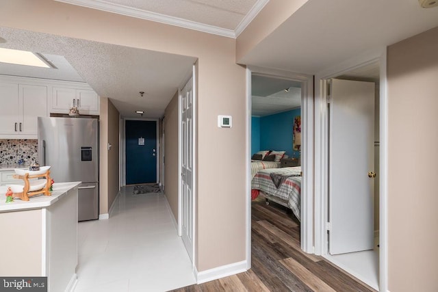 hall with wood-type flooring, ornamental molding, and a textured ceiling