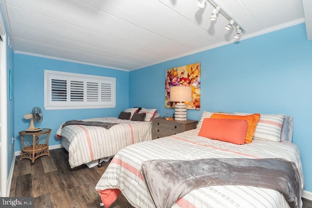 bedroom with dark hardwood / wood-style floors, crown molding, and track lighting