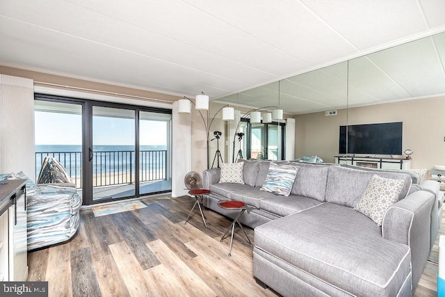 living room with hardwood / wood-style floors, a water view, and ornamental molding