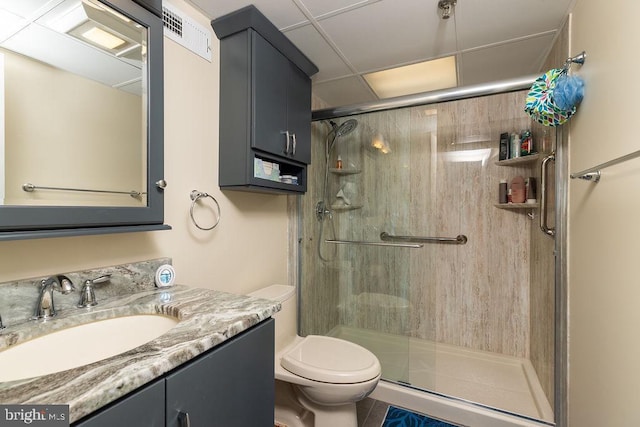 bathroom with a paneled ceiling, vanity, tile patterned flooring, toilet, and walk in shower