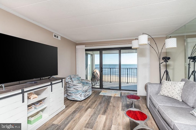 living room with a water view, wood-type flooring, and ornamental molding