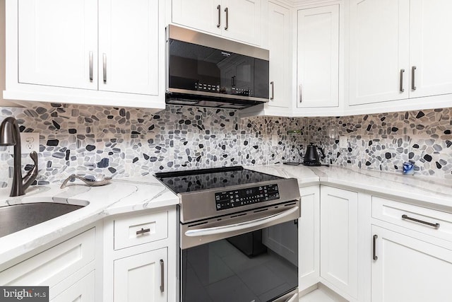 kitchen featuring white cabinets, sink, appliances with stainless steel finishes, tasteful backsplash, and light stone counters