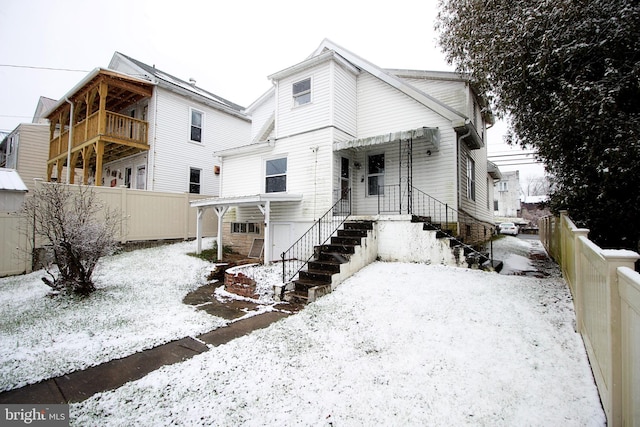 snow covered back of property with a garage