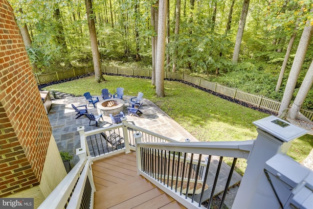 wooden terrace with an outdoor fire pit, a patio area, and a lawn