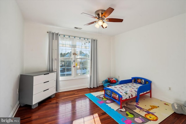 bedroom featuring ceiling fan, dark wood-type flooring, and multiple windows