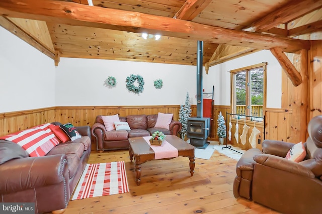 living room with a wood stove, lofted ceiling with beams, light hardwood / wood-style flooring, and wooden ceiling