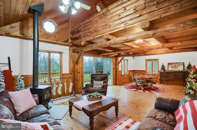 living room featuring a wood stove, beamed ceiling, wood ceiling, and light hardwood / wood-style floors