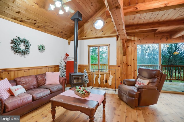 living room with light hardwood / wood-style floors, a wood stove, wooden walls, and wooden ceiling