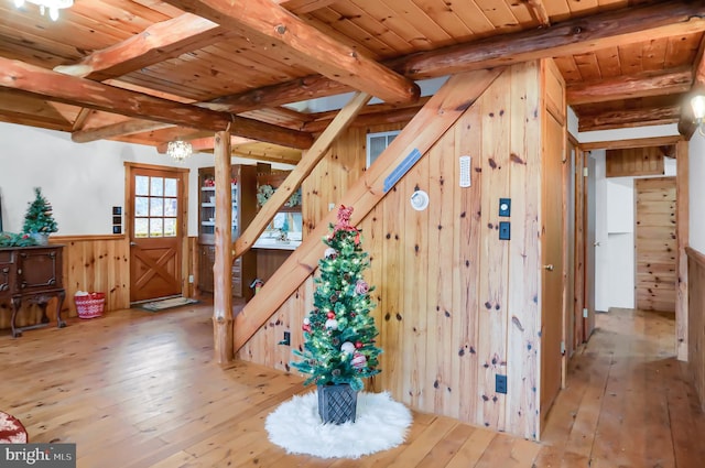 stairs featuring hardwood / wood-style flooring, beam ceiling, wooden walls, and a chandelier