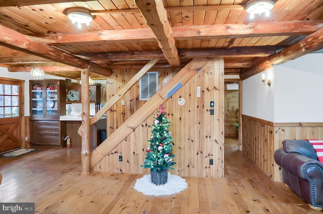 staircase with beam ceiling, hardwood / wood-style flooring, wooden walls, and wood ceiling