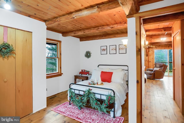 bedroom with light hardwood / wood-style flooring, beamed ceiling, and wood ceiling