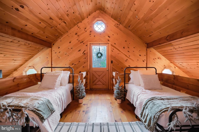 bedroom with lofted ceiling with beams, wooden walls, light hardwood / wood-style floors, and wooden ceiling