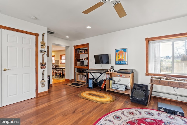 living room featuring baseboard heating, ceiling fan, and wood-type flooring