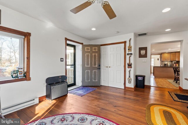 foyer entrance with ceiling fan, dark hardwood / wood-style floors, and a baseboard heating unit