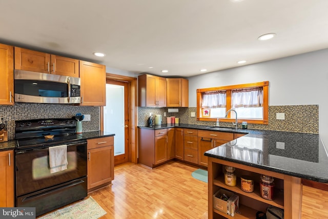 kitchen featuring backsplash, dark stone counters, sink, black / electric stove, and light hardwood / wood-style floors