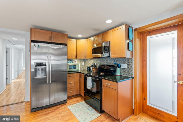 kitchen with dark stone counters, decorative backsplash, light hardwood / wood-style floors, and appliances with stainless steel finishes