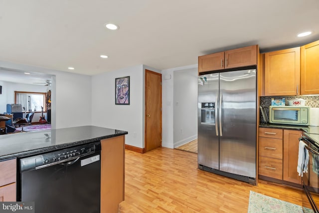 kitchen with dishwasher, stainless steel refrigerator with ice dispenser, ceiling fan, dark stone countertops, and light wood-type flooring