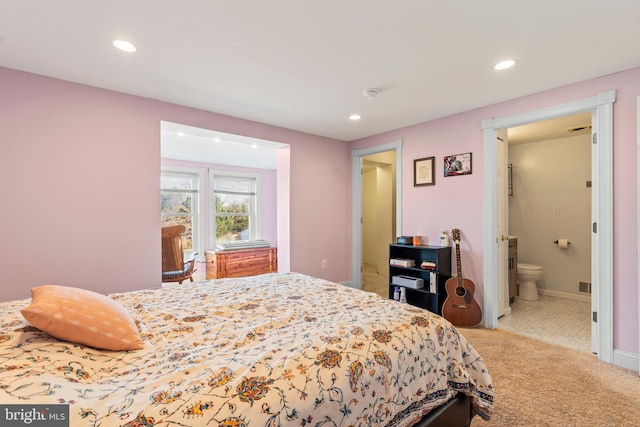 bedroom featuring ensuite bathroom and light carpet