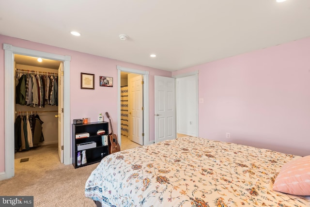 carpeted bedroom featuring connected bathroom, a walk in closet, and a closet