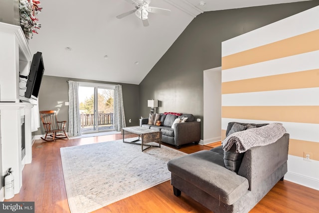 living room with ceiling fan, wood-type flooring, and vaulted ceiling