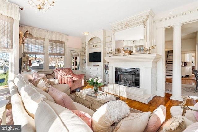 living room with dark hardwood / wood-style floors, built in features, a chandelier, and decorative columns