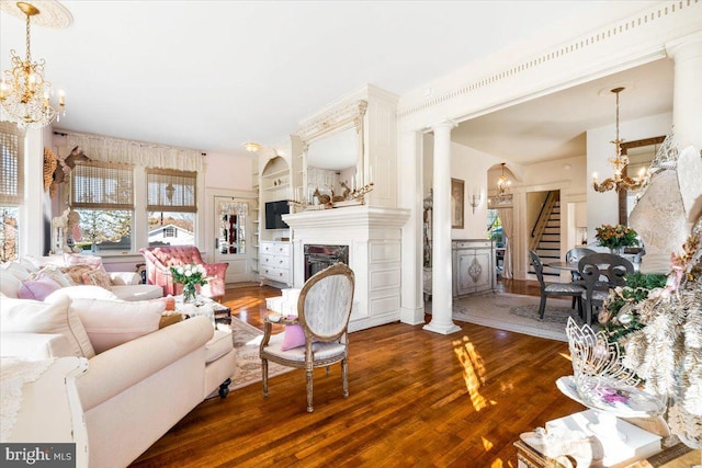 living room featuring built in shelves, dark hardwood / wood-style floors, and ornate columns