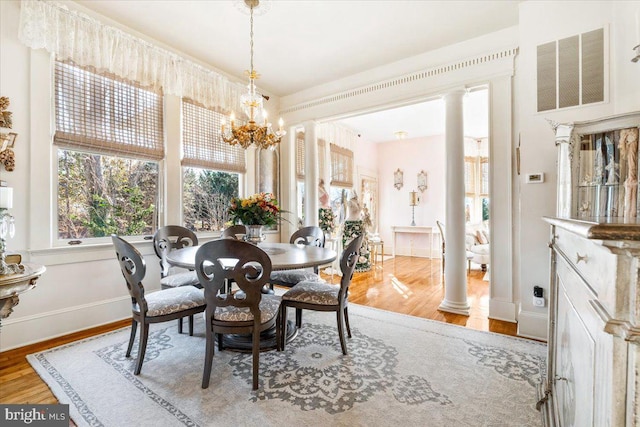 dining space featuring a chandelier, decorative columns, and light hardwood / wood-style flooring