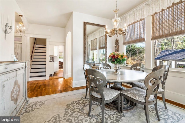 dining space with hardwood / wood-style floors and an inviting chandelier