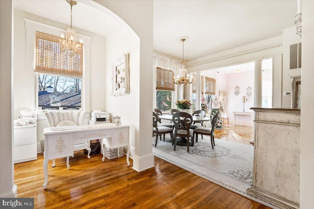 dining area with washer / dryer, a wealth of natural light, wood-type flooring, and a notable chandelier