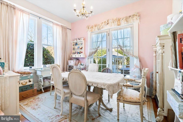 dining space with a healthy amount of sunlight, wood-type flooring, french doors, and a chandelier