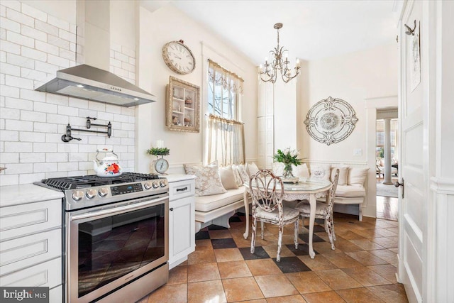 kitchen featuring white cabinetry, a wealth of natural light, stainless steel gas stove, and wall chimney exhaust hood