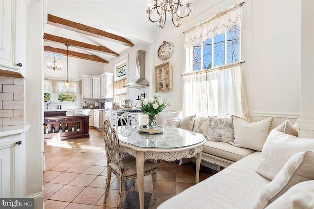 tiled dining area with beamed ceiling, breakfast area, and sink