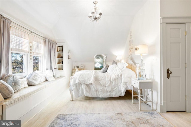 bedroom with hardwood / wood-style floors, vaulted ceiling, and a notable chandelier