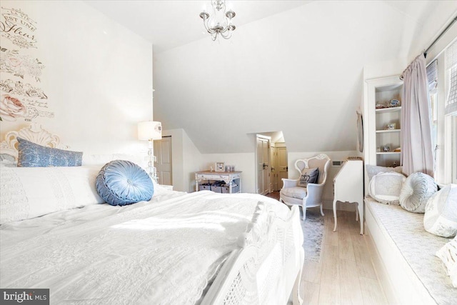 bedroom with light wood-type flooring, an inviting chandelier, and lofted ceiling