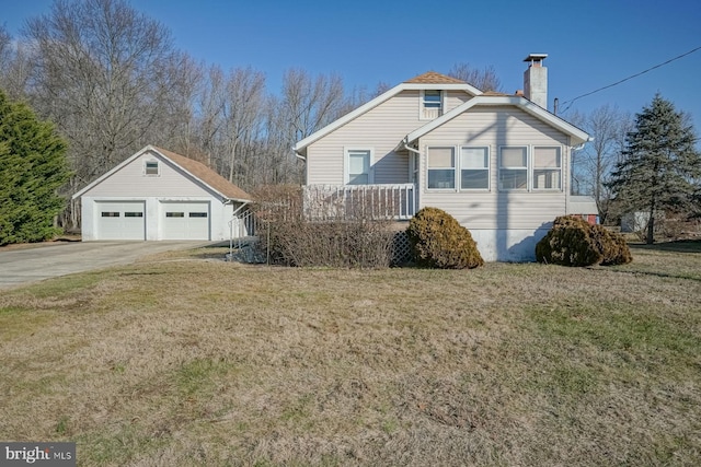 view of front of property with a garage, an outbuilding, and a front lawn