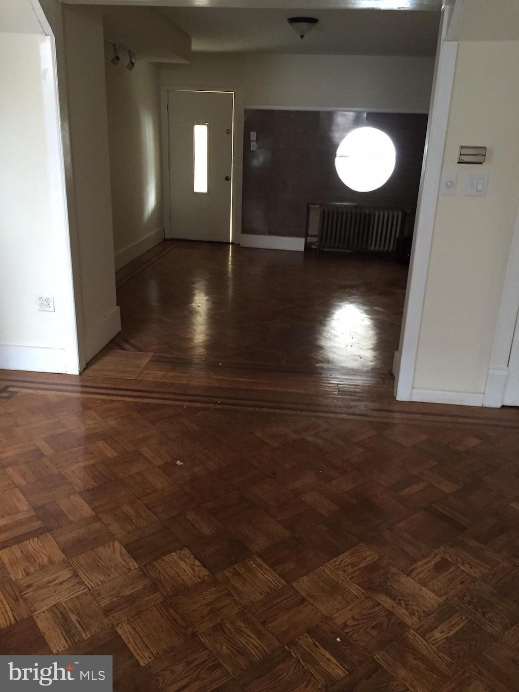 foyer entrance featuring dark parquet floors and radiator heating unit