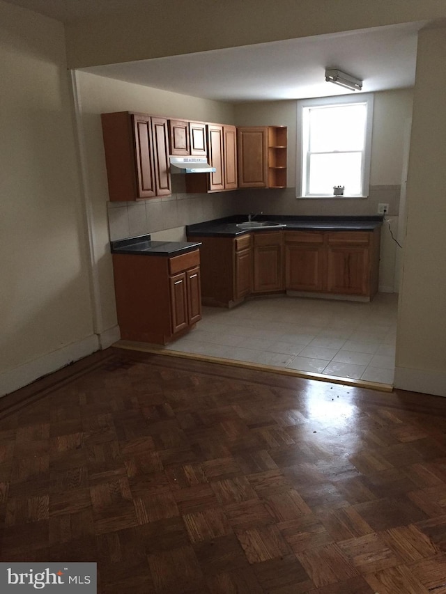 kitchen featuring dark parquet flooring, backsplash, and sink