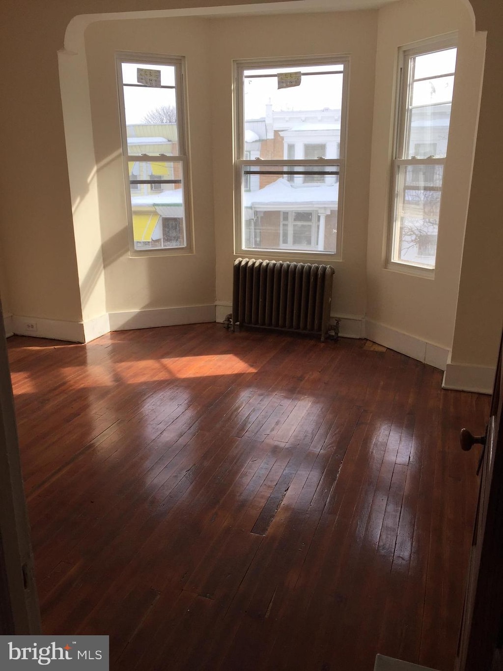 unfurnished room featuring radiator heating unit and dark hardwood / wood-style floors