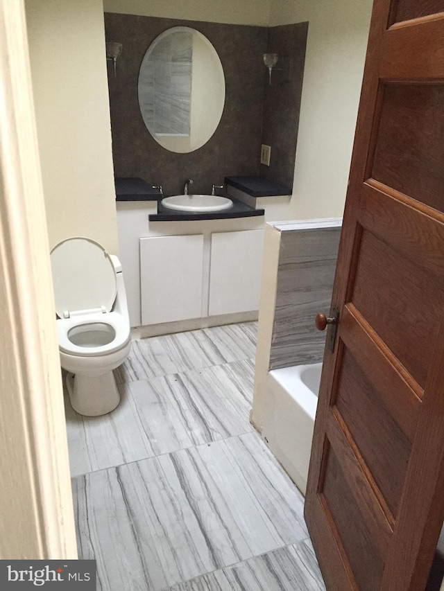 bathroom featuring vanity, toilet, and a bath