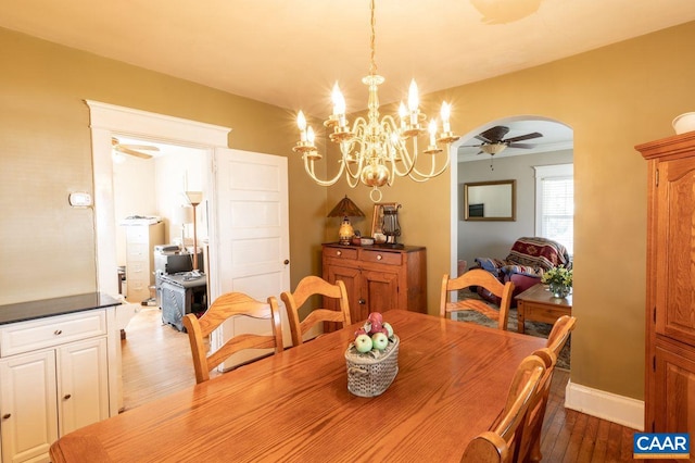 dining space with dark hardwood / wood-style flooring and ceiling fan with notable chandelier